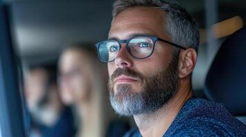 A man with glasses and beard sitting in a car photo