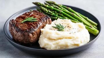 A plate with a steak, mashed potatoes and asparagus photo