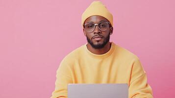 A man in a yellow hat and glasses is using a laptop photo