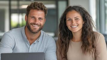 A man and woman smiling while sitting in front of a laptop photo