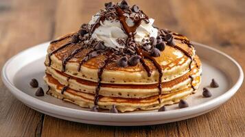 A stack of pancakes topped with chocolate chips and whipped cream photo