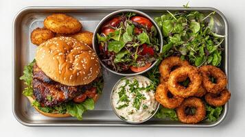 A tray with a burger, onion rings, salad and other food photo