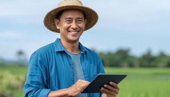 Happy asian farmer in green fields using tablet rural landscape bright daylight joyful mood photo