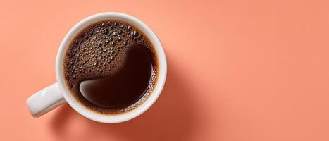 Topdown view of white mug filled with steaming coffee on coral background photo