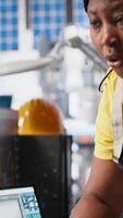 Vertical African american team programs robotic arms in solar panel manufacturing facility, working on creating solar cells for eco friendly alternative energy. Sustainable solutions in factory. Camera A. video