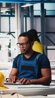 Vertical Black engineer implements automation logic in solar factory software, working on manufacturing solar panel designs for alternative energy. High tech production line. Camera B. video