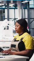 Vertical Engineer configures solar panel systems on PC in modern factory, working on energy optimization software. Expert manages photovoltaic operations in a high tech, automated facility. Camera A. video