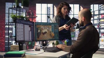 Architectural design team configures a floor plan on dual monitors, utilizing computer aided design tools. Colleagues use software for digital rendering and interior decoration remodeling. Camera A. video