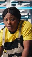 Vertical African american team programs robotic arms in solar panel manufacturing facility, working on creating solar cells for eco friendly alternative energy. Sustainable solutions in factory. Camera B. video