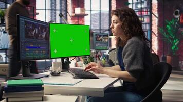 Woman creator edits a multimedia project next to chroma key at agency office, using professional tech tools and editing software to manage timeline editing and production. Camera A. video