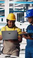 Vertical Solar panels engineers team developing new photovoltaic materials using devices in the manufacturing plant. Black workers group conducting experiments for better production line. Camera B. video