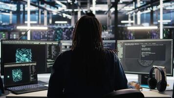 Data center system administrator using machine learning algorithms to analyze large datasets. Server farm worker using AI neural networks on computer to recognize data patterns, camera A video