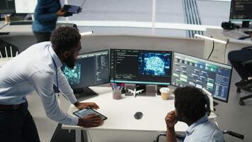 Technician in wheelchair and data center manager using AI node tree software to minimize system downtime. Server hub employee in disability and team leader using visual programming tool, camera A video