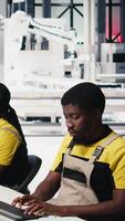 Vertical Black employee manages solar panel configuration via desktop tools, optimizing factory output and troubleshooting. Technician updates energy system parameters on pc. Camera B. video