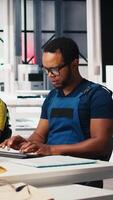 Vertical Employee uses computer to control robotic arms in solar factory in a high tech sustainable facility. Technician adjusts automation settings to support consistent manufacturing. Camera B. video