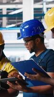 Vertical Solar panels engineers team developing new photovoltaic materials using devices in the manufacturing plant. Black workers group conducting experiments for better production line. Camera A. video