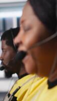 Vertical Customer support black engineer at help desk in photovoltaic facility answering calls on headset, offering assistance and support in fixing technical issues. Female operator on help line. Camera A. video