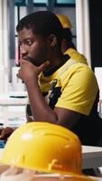 Vertical Male specialist adjusts machine parameters for solar panel production, working at a high tech manufacturing plant. Black engineer analyzing technical data on a computer. Camera B. video