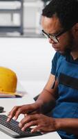 Vertical Engineer investigating malfunctioning systems in photovoltaics factory, comparing parameters with pc and tablet. Black man inspecting solar panels manufacturing plant, high tech. Camera A. video