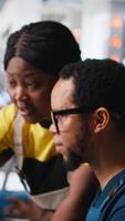 Vertical Black engineers collaborate on photovoltaic system designs at computer, focused on eco friendly renewable technology. Team finetuning solar power software and equipment performance. Camera A. video