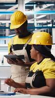 Vertical African american team of employees doing quality control on pc, troubleshooting and fixing technical issues for solar panel production at the factory. Coworkers inspecting system. Camera B. video