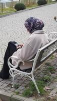 Woman sitting on bench using phone in a peaceful park setting video