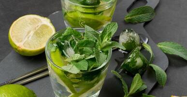Refreshing mojito cocktail with lime, mint, strawberry, and ice on dark background, top view. photo