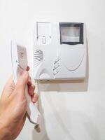 Hand holding intercom receiver. Security concept. Communication with visitor. Control, access, safety. Use for home, building, apartment themes. photo