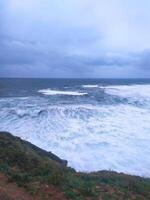 Dramatic seascape with crashing waves under a stormy sky. A powerful visual representing strength, resilience, and the raw beauty of nature. Ideal for travel, weather, or inspirational content. photo