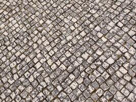 Highangle view of a weathered cobblestone pavement, showcasing a textured diamond pattern. photo