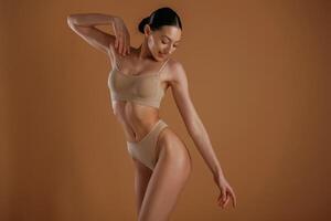 Creamy colored ,,underwear. Woman with slim body shape is posing against background photo