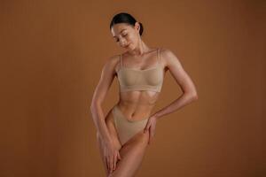 Creamy colored underwear. .Woman ,with slim body shape is posing against background photo