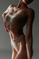 In the sunlight, shadows. Woman with slim body shape is posing against background.. photo