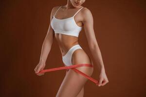 Measuring, the leg, conception ,of weight loss. Woman with slim body shape is posing against background photo