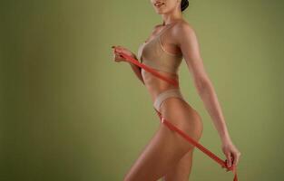 Results of diet, with, measuring tape. Woman with slim body shape is posing against background photo