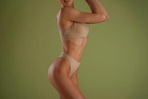 Side ,close up view. Woman with slim body shape is posing against background photo