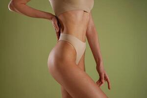 Side, close up view. Woman with slim body shape is posing against background photo