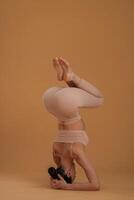 Doing headstand. Beautiful fitness woman is in the studio photo