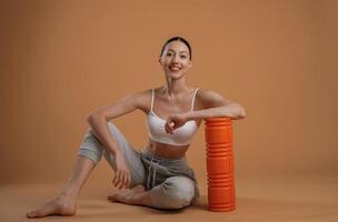 On the floor, sitting. Beautiful, fitness woman is in the studio photo