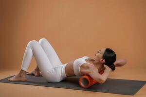 Using ,,roll on the yoga mat. Beautiful fitness woman is in the studio photo