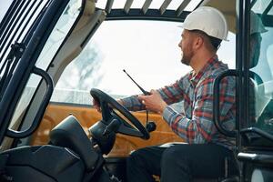 Using radio, talking. Man is with tractor. Agricultural worker.. photo