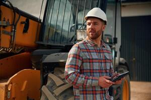 Digital tablet in hands.., Man is with tractor. Agricultural worker photo