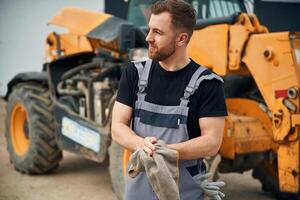 Cleaning the, hands after job is done, mechanic. Man is with tractor. Agricultural worker photo