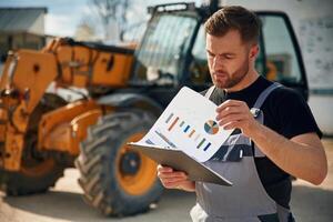 Data in, the,, notepad, reading. Man is with tractor. Agricultural worker photo