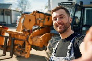 Making selfie, smiling. Man ,is with tractor. Agricultural worker photo