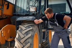 Checking the, wheel. Man is with tractor. Agricultural worker photo