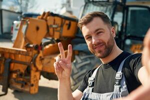 Making ,selfie, smiling. Man is with tractor. Agricultural worker photo