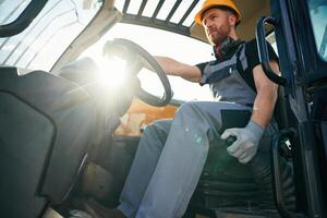 Sitting in, the vehicle. Man is with tractor. Agricultural worker photo