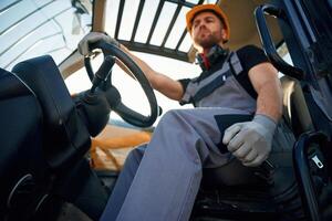 Sitting, in the vehicle. Man is with tractor., Agricultural worker photo