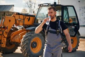 Drinking water,,, taking a break, tired. .Man is with tractor. Agricultural worker photo